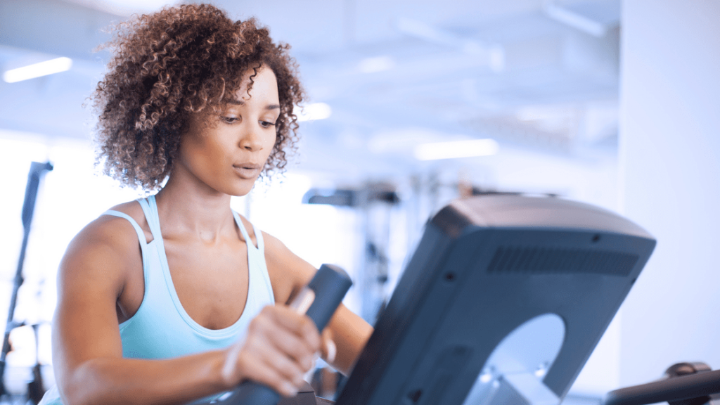 Mulher treinando em elíptico na academia